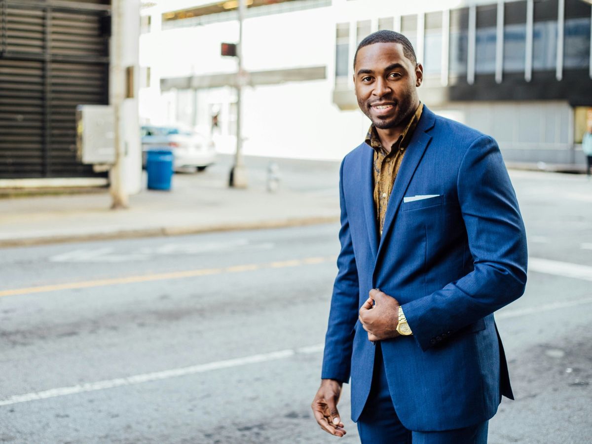 A smiling professional in a blue suit on a city street